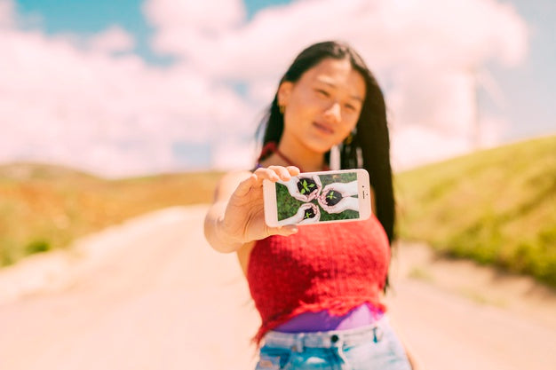 Free Asian Woman Presenting Smartphone Mockup In Nature Psd